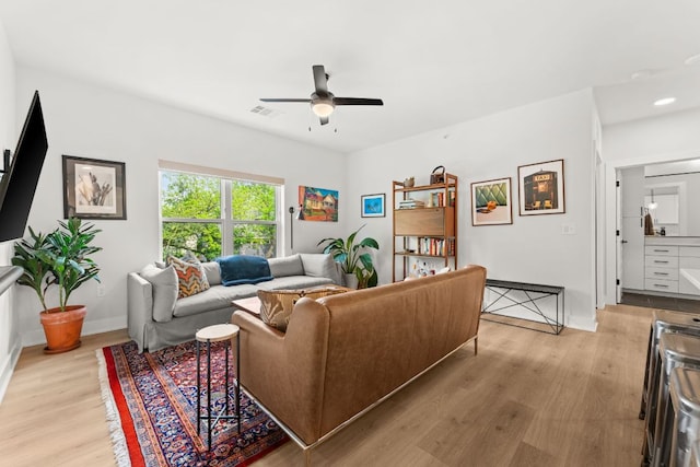 living area with baseboards, a ceiling fan, light wood-type flooring, and visible vents