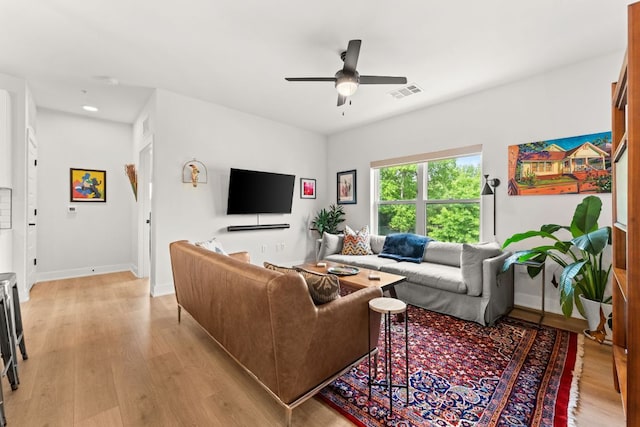 living room with baseboards, a ceiling fan, light wood-type flooring, and visible vents