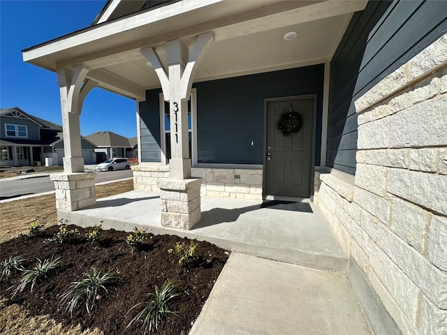view of exterior entry with a porch and stone siding