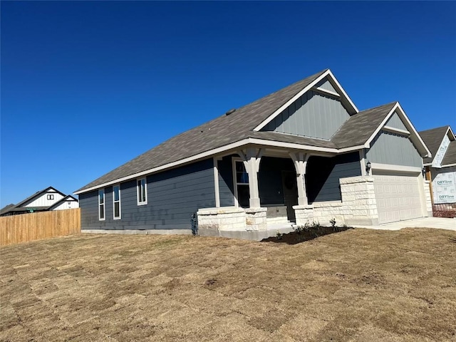 view of front of house with a garage, fence, covered porch, board and batten siding, and driveway