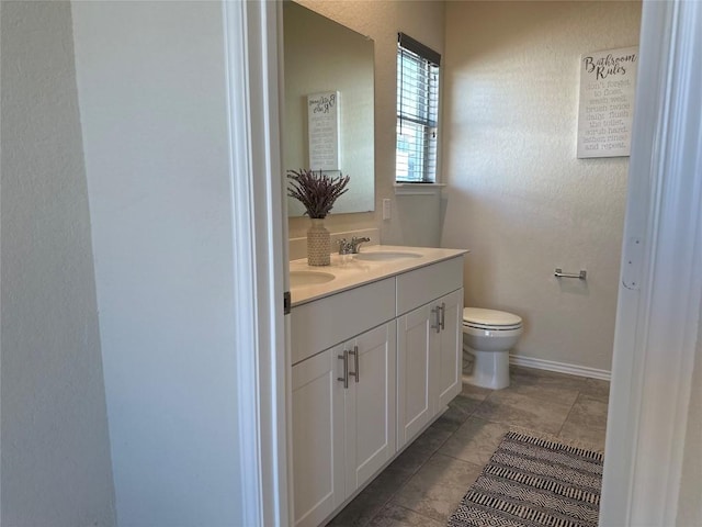 full bathroom with double vanity, a sink, baseboards, tile patterned floors, and toilet