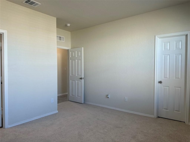 unfurnished bedroom with light colored carpet, baseboards, and visible vents
