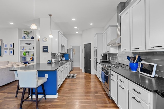 3907 Becker Ave, Austin, TX 78751 - kitchen with appliances with stainless steel finishes, dark countertops, wall chimney exhaust hood, a kitchen breakfast bar, and open floor plan