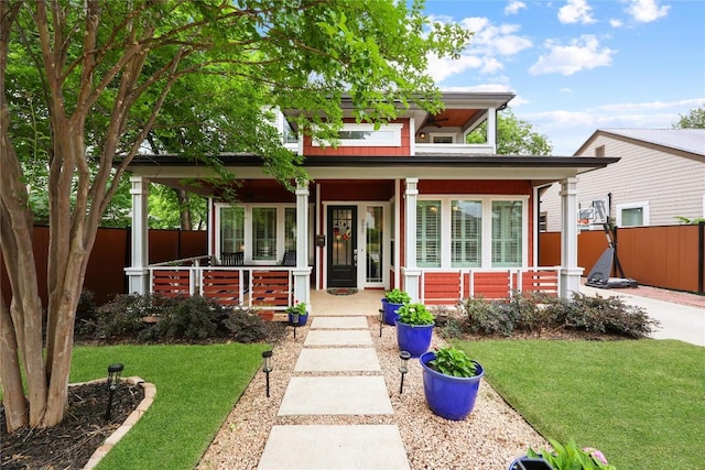 bungalow-style house featuring fence, covered porch, and a front lawn