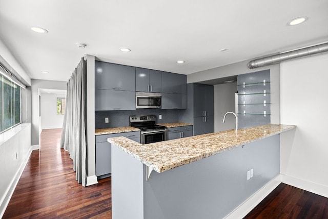 kitchen with a peninsula, appliances with stainless steel finishes, gray cabinets, and modern cabinets