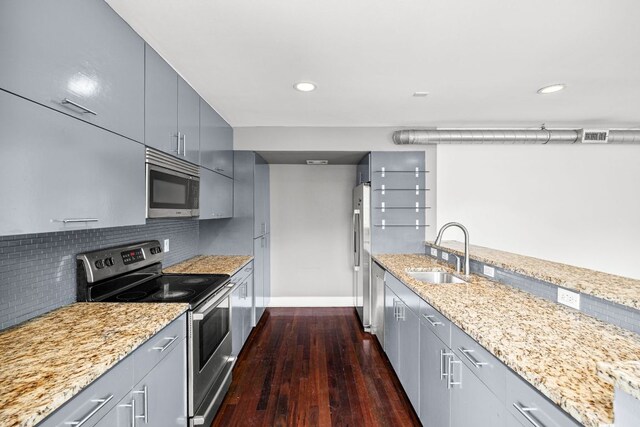 kitchen with dark wood finished floors, a sink, baseboards, gray cabinetry, and stainless steel appliances