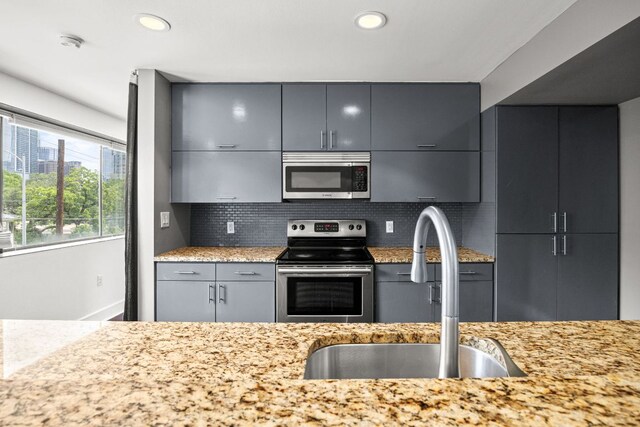 kitchen featuring a sink, appliances with stainless steel finishes, gray cabinets, and decorative backsplash