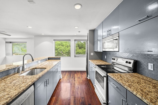 kitchen featuring light stone countertops, dark wood-style floors, tasteful backsplash, a sink, and appliances with stainless steel finishes