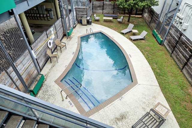 community pool with a lawn, a fenced backyard, and a patio