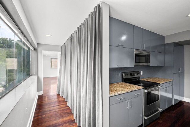 kitchen with decorative backsplash, appliances with stainless steel finishes, dark wood finished floors, gray cabinetry, and baseboards