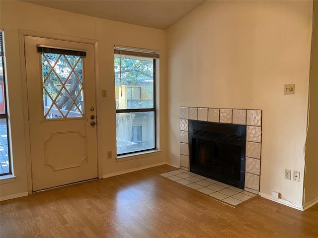 entryway with baseboards, wood finished floors, and a fireplace