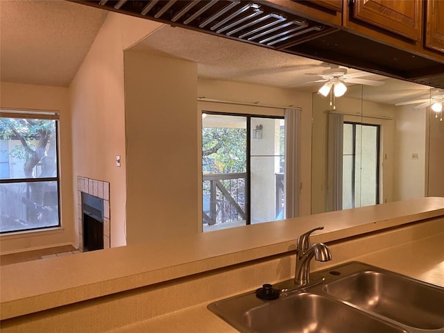 kitchen featuring a sink, light countertops, ceiling fan, and a healthy amount of sunlight