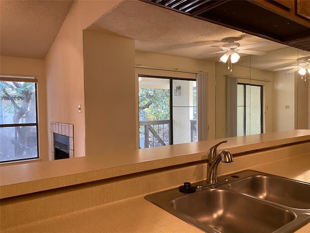kitchen featuring a sink, a textured ceiling, a ceiling fan, and a healthy amount of sunlight