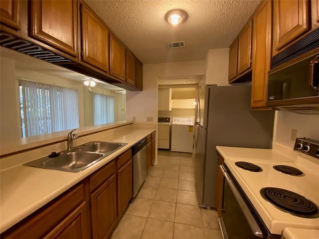 kitchen with stainless steel dishwasher, black microwave, white range with electric cooktop, washing machine and clothes dryer, and a sink