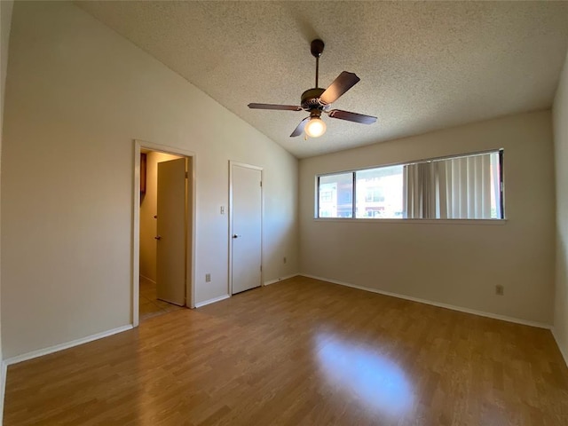 unfurnished bedroom featuring baseboards, vaulted ceiling, a textured ceiling, and wood finished floors