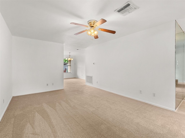 empty room with light carpet, ceiling fan with notable chandelier, and visible vents