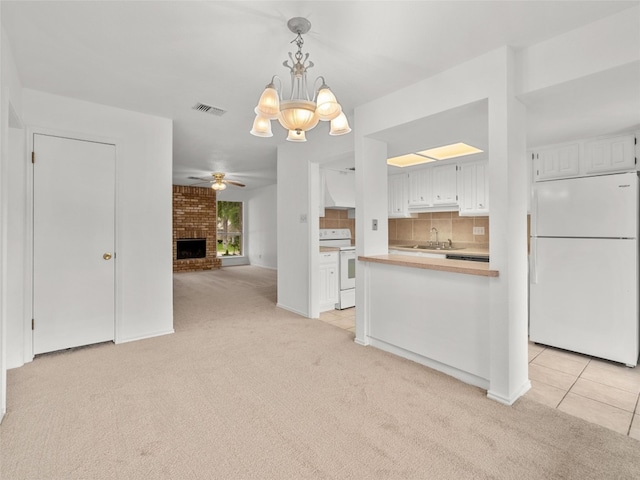 kitchen featuring visible vents, ceiling fan with notable chandelier, light carpet, and white appliances