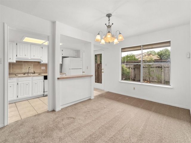 interior space featuring an inviting chandelier, baseboards, light colored carpet, a sink, and light tile patterned floors