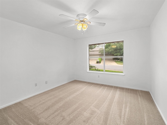 carpeted spare room with baseboards and ceiling fan