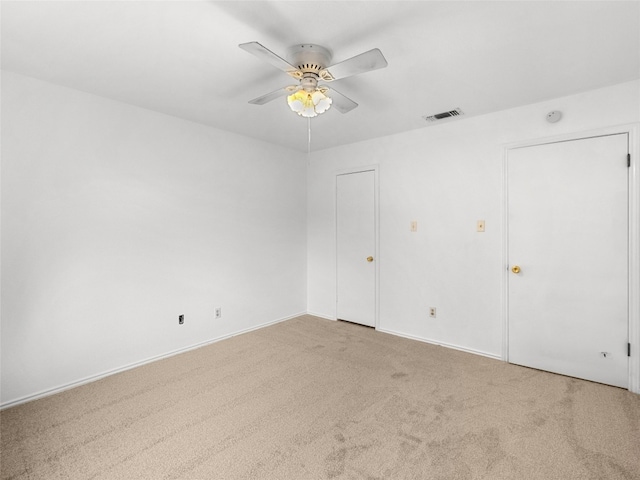 carpeted spare room featuring ceiling fan, visible vents, and baseboards