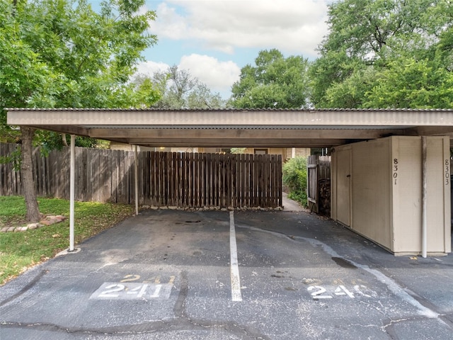 covered parking lot featuring fence