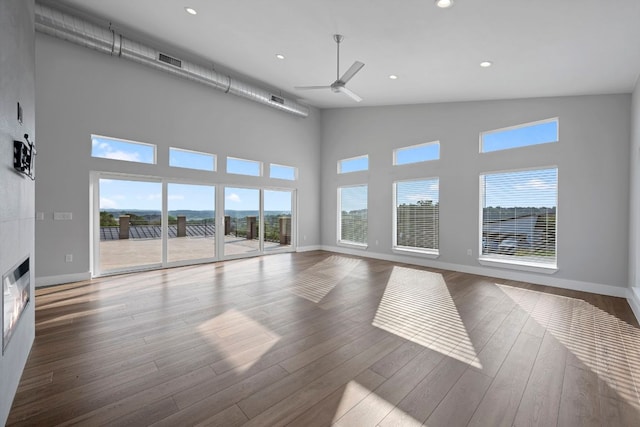 3503 Constitution Dr, Lago Vista, TX 78645 - unfurnished living room with ceiling fan, a towering ceiling, wood finished floors, recessed lighting, and a glass covered fireplace