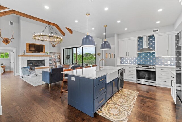 kitchen featuring visible vents, wall chimney exhaust hood, white cabinetry, a sink, and appliances with stainless steel finishes