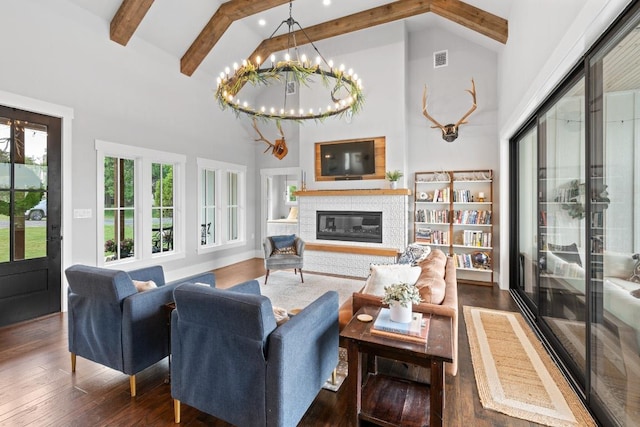 living area with beam ceiling, high vaulted ceiling, a glass covered fireplace, wood finished floors, and visible vents