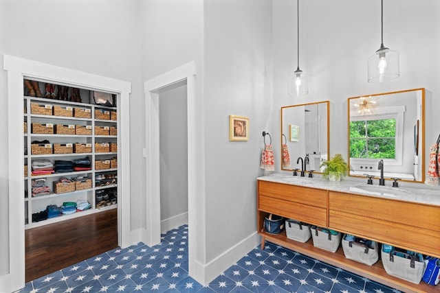 bathroom with a sink, baseboards, a high ceiling, and double vanity
