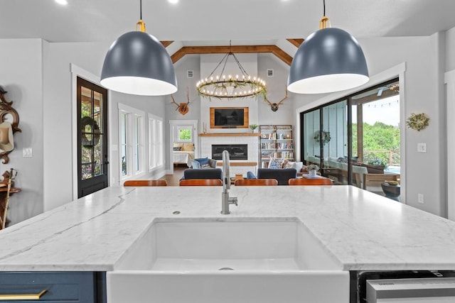kitchen featuring light stone countertops, vaulted ceiling, a sink, open floor plan, and dishwashing machine