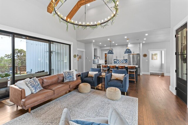 living area with dark wood-style flooring, a high ceiling, a notable chandelier, and baseboards