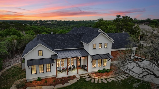 back of property with a standing seam roof, metal roof, and roof with shingles
