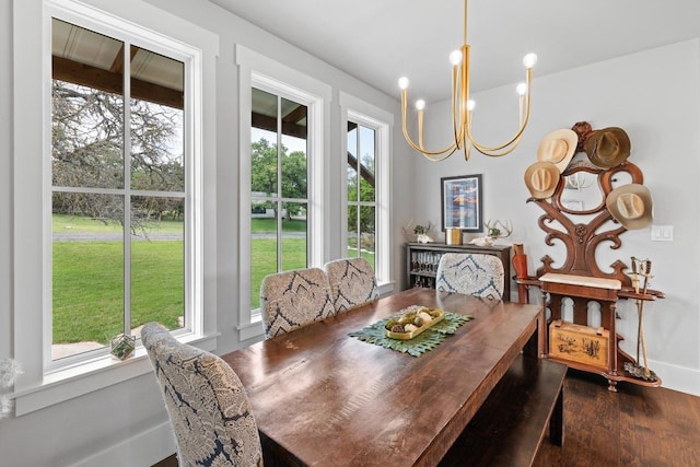 dining area featuring baseboards, wood finished floors, and a notable chandelier