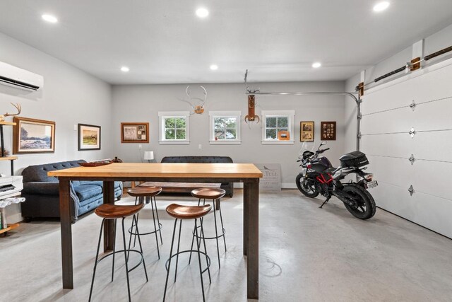 interior space with a breakfast bar area, concrete flooring, recessed lighting, and a wall mounted air conditioner