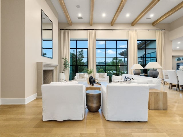 living room featuring recessed lighting, baseboards, beam ceiling, and light wood-style flooring