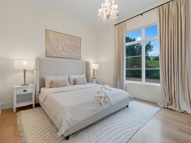 bedroom with baseboards, wood finished floors, and a chandelier