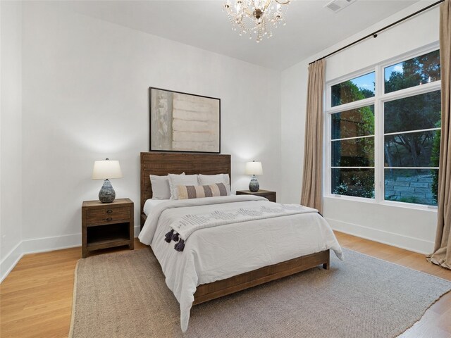 bedroom featuring light wood-type flooring, baseboards, a chandelier, and visible vents