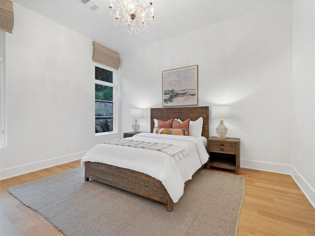 bedroom with a notable chandelier, visible vents, baseboards, and light wood-type flooring