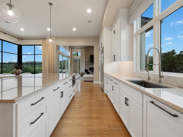 kitchen featuring visible vents, light stone countertops, recessed lighting, a sink, and light wood-style flooring