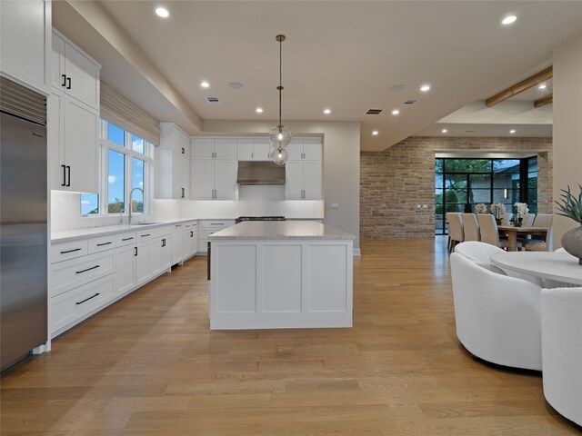 kitchen featuring light wood-style floors, built in fridge, a center island, white cabinetry, and open floor plan