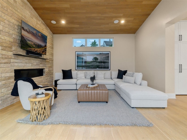 living room with wood ceiling, a stone fireplace, wood finished floors, lofted ceiling, and recessed lighting