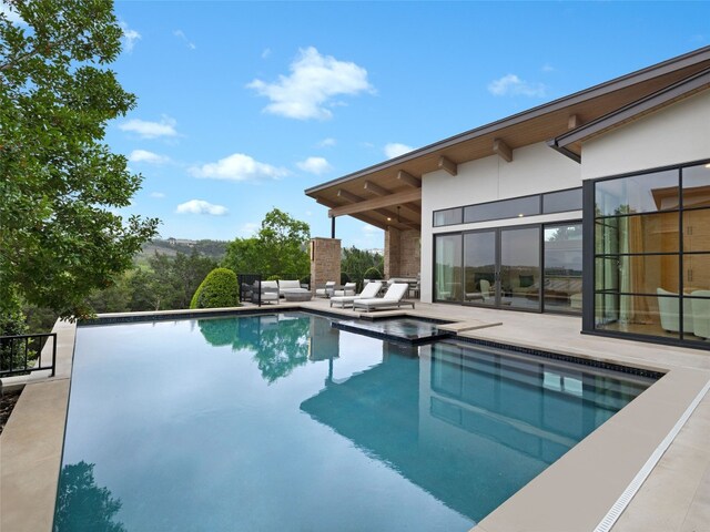 view of pool with a patio area and a pool with connected hot tub