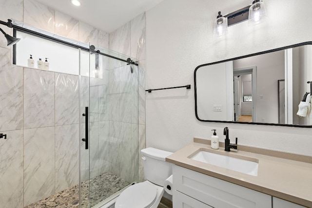 full bath with vanity, a stall shower, and toilet