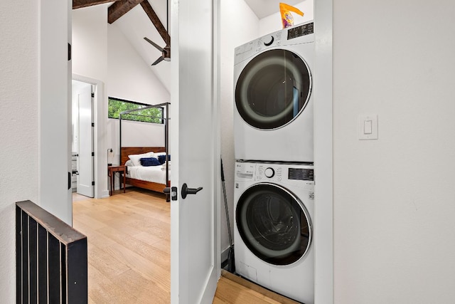 clothes washing area with a high ceiling, stacked washing maching and dryer, wood finished floors, and ceiling fan