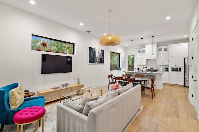 living room with light wood-style floors, baseboards, recessed lighting, and visible vents