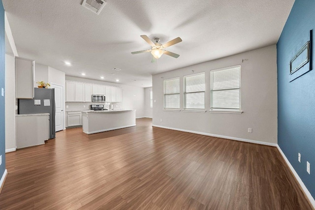13601 Primrose Petal Dr, Manor, TX 78653 - unfurnished living room with a ceiling fan, dark wood finished floors, baseboards, a textured ceiling, and recessed lighting