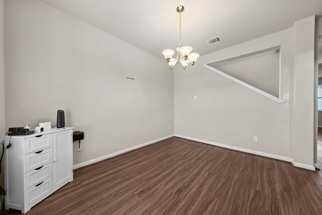 unfurnished room with a notable chandelier, visible vents, baseboards, and dark wood-type flooring