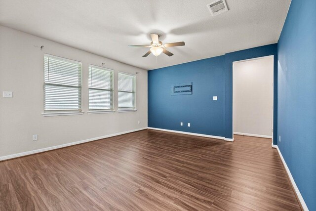 spare room with a ceiling fan, baseboards, visible vents, and wood finished floors