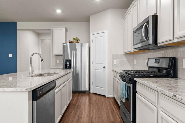 kitchen with white cabinets, a sink, stainless steel appliances, tasteful backsplash, and dark wood-style floors