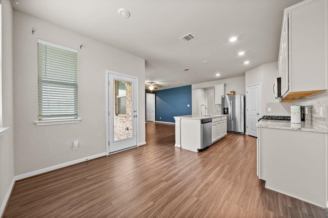 kitchen with visible vents, baseboards, open floor plan, stainless steel appliances, and an island with sink